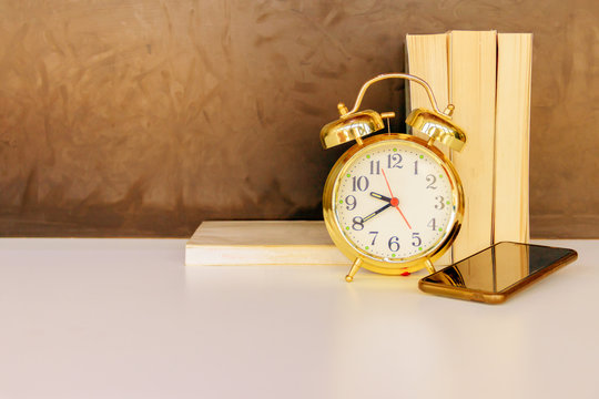alarm clock old vintage gold and mobile phone, book over white on black background. with copy space add text