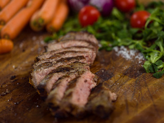 Juicy slices of grilled steak on wooden board