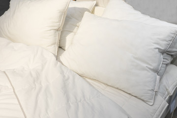 white pillow on bed and with wrinkle messy blanket in bedroom, from sleeping in a long night, an unmade bed in hotel bedroom with white blanket.