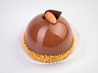 Mini mousse pastry dessert covered with chocolate velour and decorated with brown glaze and almond isolated on white background. Modern european cake. French cuisine.