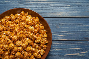 Delicious popcorn with caramel on wooden background, top view