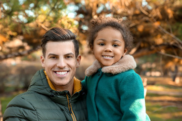 Young man and little African-American girl outdoors on sunny day. Child adoption
