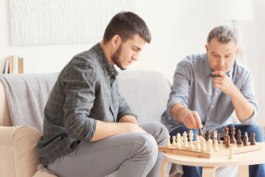 Mature Man Playing Chess With His Son At Home