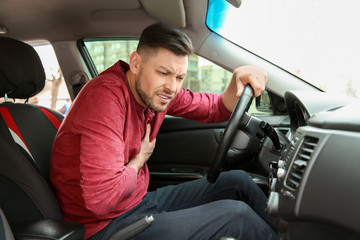 Mature man suffering from heart attack in car