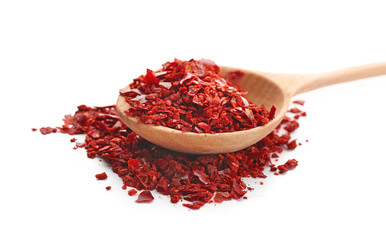 Wooden spoon and chili pepper flakes on white background
