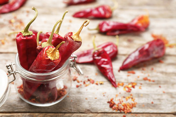 Jar with dry chili peppers on table
