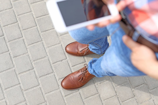Man in stylish leather shoes using mobile phone outdoors, closeup