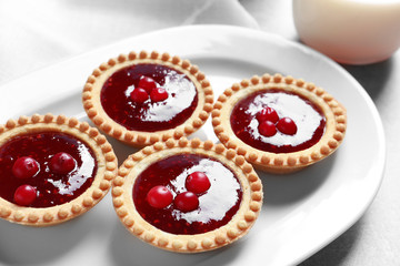 Tasty tartlets with jam on plate, closeup