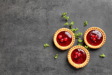 Tasty tartlets with jam on grey background, top view