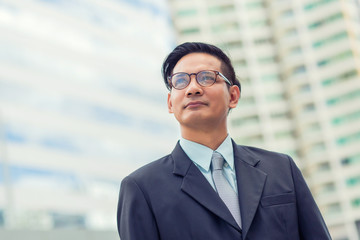 Asia young business man in front of the modern building in downtown .Concept of young  business people