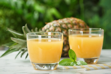 Composition with delicious pineapple juice on table against blurred background