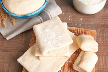 Fresh raw dough on wooden board, closeup