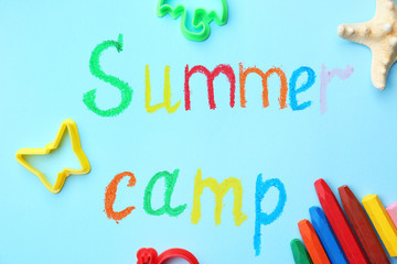 Flat lay composition with words SUMMER CAMP and crayons on color background