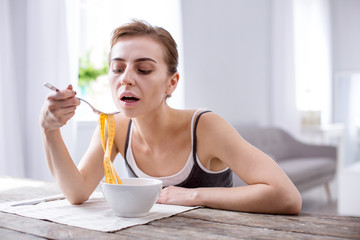 Health problem. Pleasant young woman trying to eat while suffering from anorexia