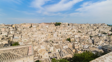 Fototapeta na wymiar panoramic view of typical stones Sassi di Matera and church of Matera under blue sky with clouds