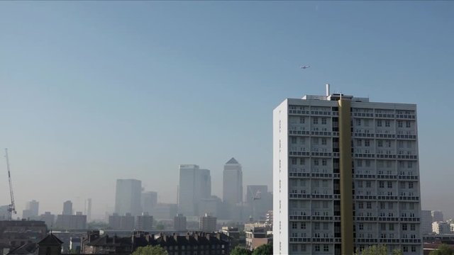 UK May 2018 - Passenger jet planes pass over Canary Wharf financial district which is shrouded in smog as London suffers a &ldquo;Code Red&rdquo; air pollution warning.