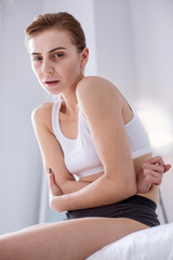 Acute pain. Ill young woman holding her stomach while feeling a strong pain