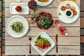 breakfast served cafe table with cheese pancakes, sandwich, croissant and drinks. Top view