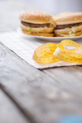 Obraz na płótnie Canvas Danger of fast food. Centimeter tape lying on the table near hamburgers