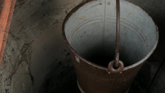 empty metal bucket hanging in a rural well