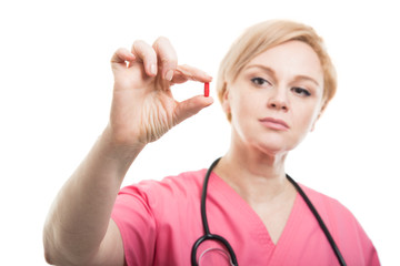 Selective focus of female nurse wearing pink scrubs showing pill