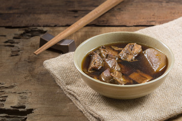asian style tender boiled beef soup in a ceramic bowl on wooden table. healthy food concept.
