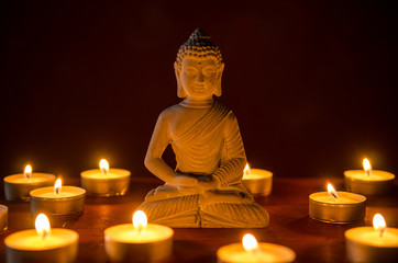 Fototapeta premium little buddha statue surrounded by tea candles