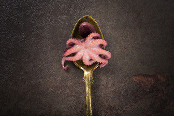 Small marinated octopus on a golden spoon