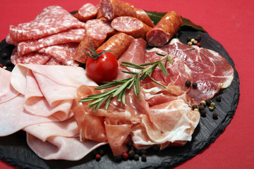 Food tray with delicious salami, ham,  fresh sausages and herbs. Meat platter with selection
