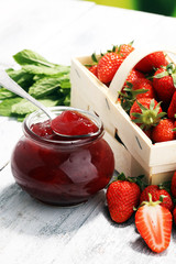 Strawberry jam in a jar and fresah strawberries.