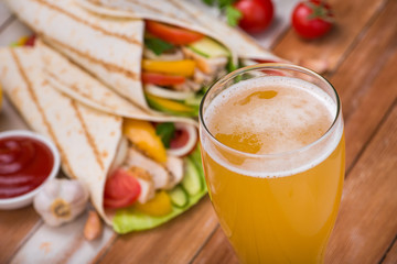 Tortilla wraps with grilled chicken and fresh vegetables and glass of beer