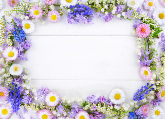 Floral layout, creative flower composition. Wreath framefrom lilac and pink daisies on white wooden background, top view. Flat lay, copy space, macro.