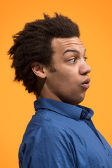 Obraz premium The young attractive man looking suprised isolated on orange