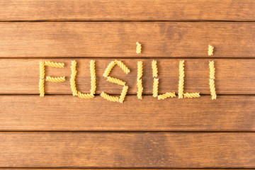 Uncooked fusilli pasta . On a wooden table . Italian food