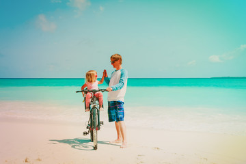 father with little daughter biking on beach