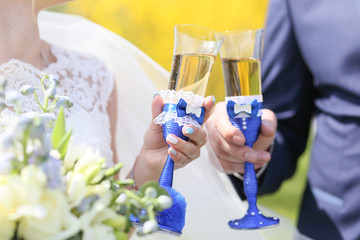 Hands of newlyweds holding wedding glasses in the open air