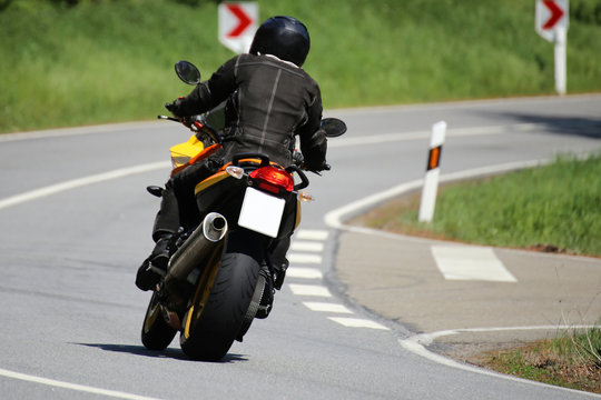 Motorradfahrer auf einer kurvenreichen Landstraße
