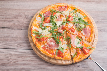 Fresh pizza with prosciutto meat, tomato and green arugula