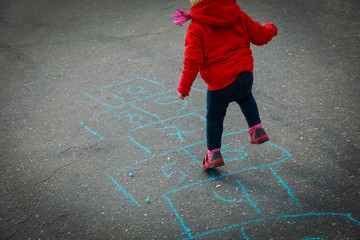 little girl play hopscotch on playground