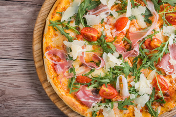Fresh pizza with prosciutto meat, tomato and green arugula