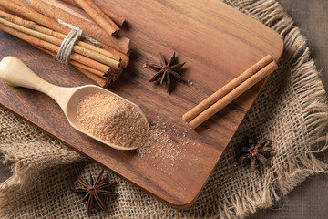 Fototapeta na wymiar brown sugar on wood scoop and cinnamon sticks