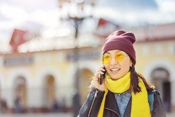 Portrait of beautiful asian hipster young woman using her mobile smart phone in the street