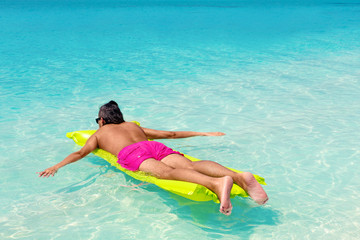 Man with inflatable green mattress on beach