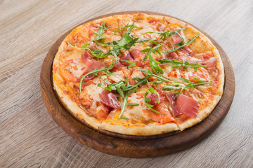 Fresh pizza with prosciutto meat, tomato and green arugula
