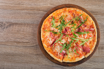 Fresh pizza with prosciutto meat, tomato and green arugula