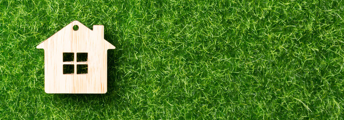 Model of wooden house on green grass background