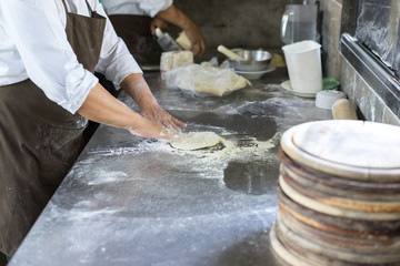 Hands kneading dough for pizza making, chef preparing base for making traditional italian meal.
