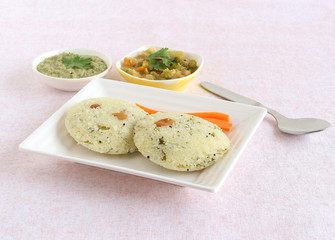 Rava idli, or semolina cake, south Indian traditional, popular and vegetarian breakfast with coconut chutney and vegetable curry as side dishes, is a steam-cooked food.
