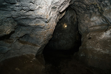 Beautiful cave. View from inside dark dungeon. Textured walls of cave. Background image of underground tunnel. Dampness inside cave. Lighting inside cave for excursions.
