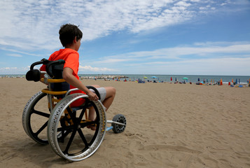 boy looks at the sea from a wheelchair